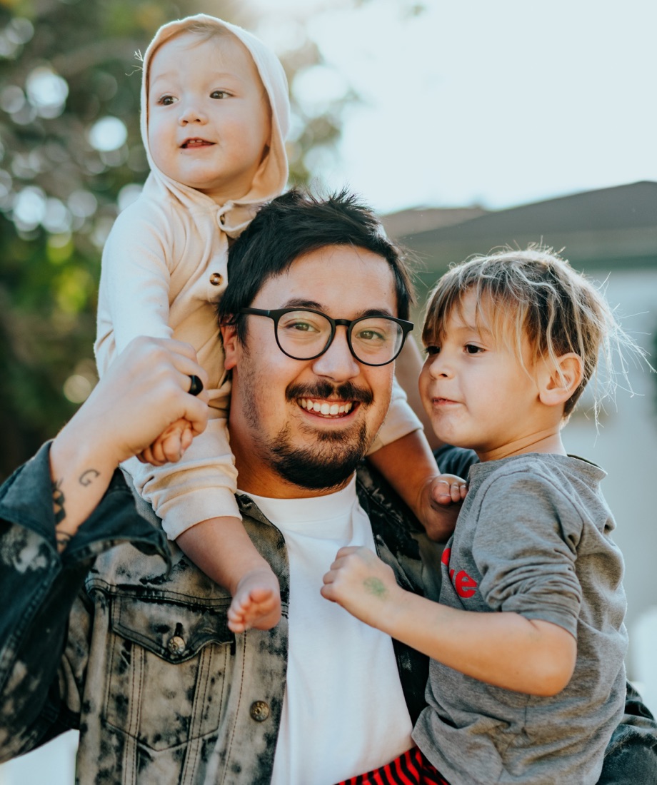 Person smiling and holding young children in arms